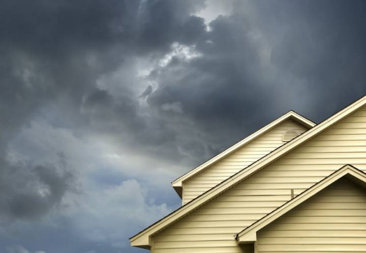Roof gables of weatherboard house with dark storm clouds in the background