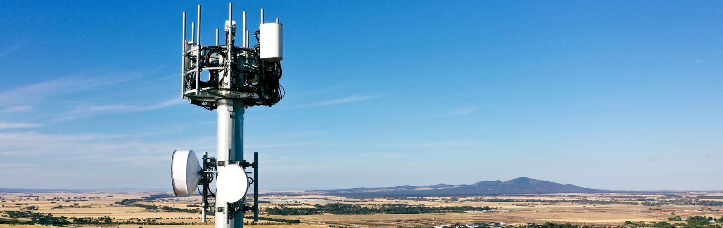 An aerial view of one of nbn's Fixed Wireless towers with blue sky, paddocks and hills in the background